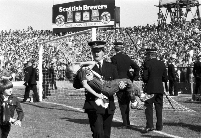 A policeman carries LIttle boy injured after crowd trouble during the Hibs v Hearts Edinburgh